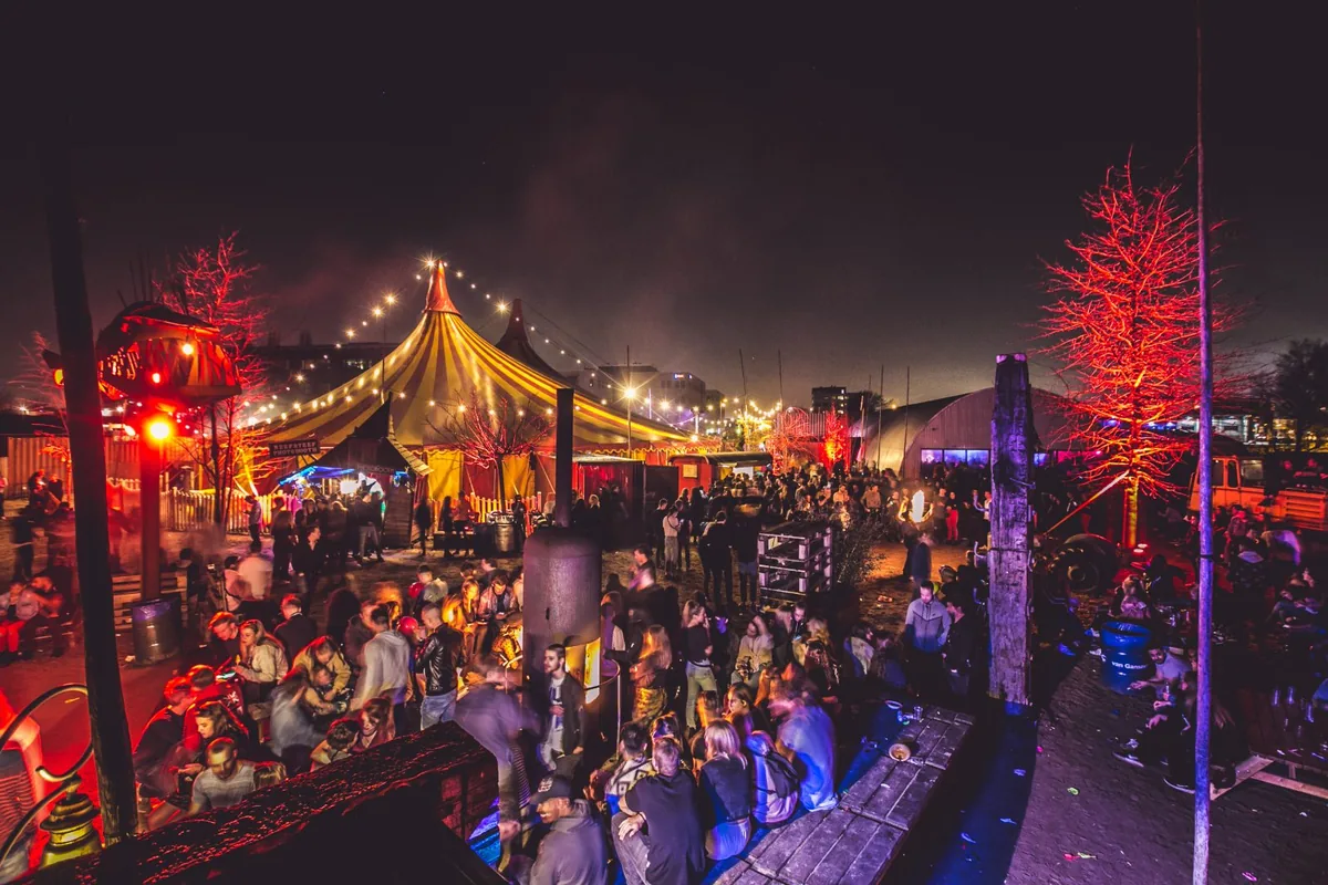 Thuishaven festivalterrein bij avond — verlichte tenten en publiek